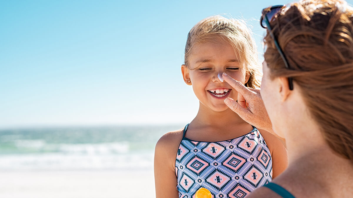 A woman applying sunscreen to her daughter's nose