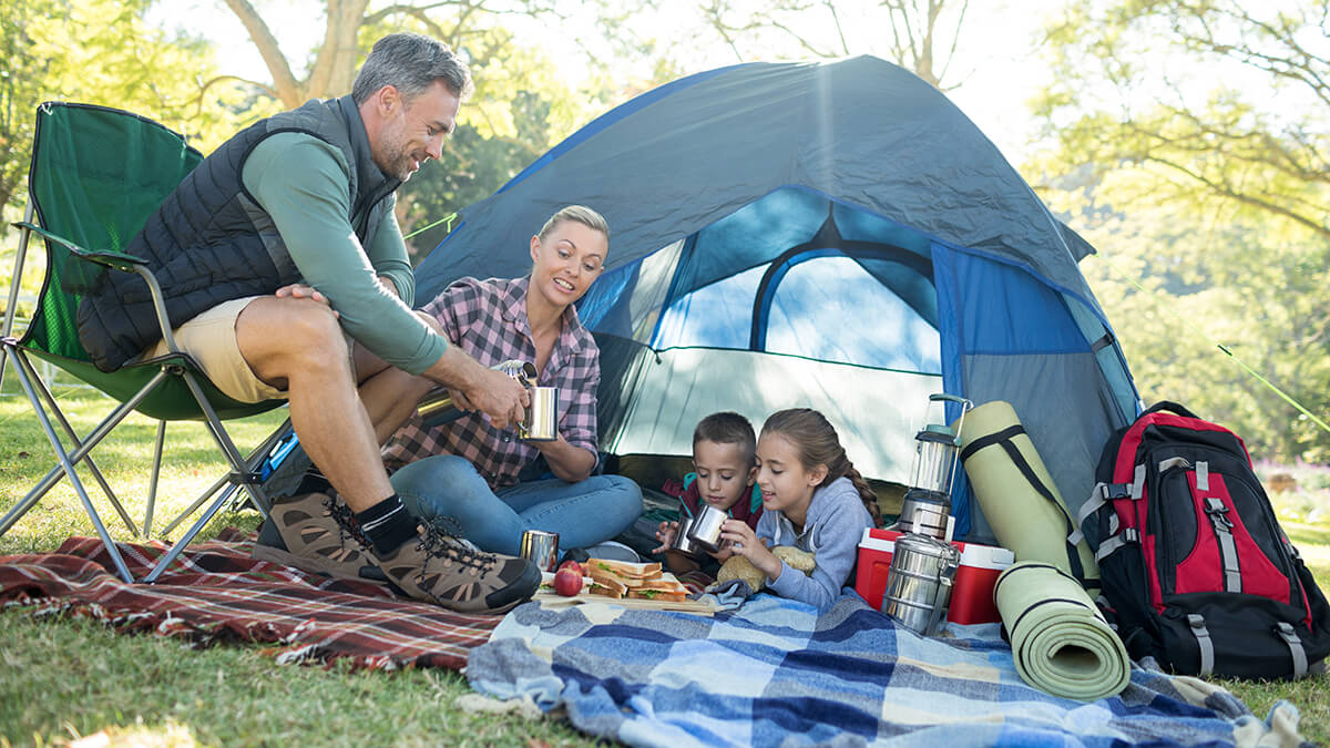 A family by a tent sharing a meal