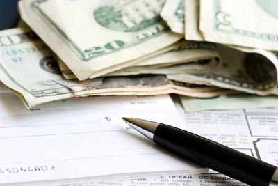 A close-up of money, a check, a form, and pen