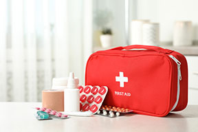 A red first aid kit bag with supplies to keep in your first aid bag.