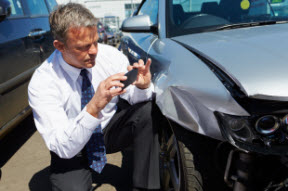 Man taking a picture of car damage with cell phone