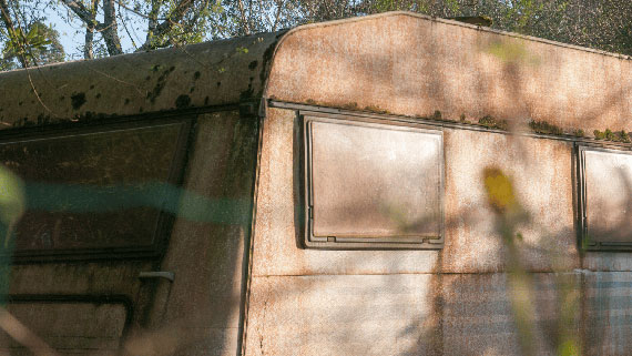 A weathered and abandoned camper van sitting in the country side.