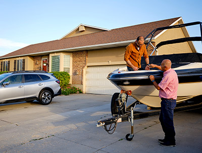 two men working on a boat next to a home and auto