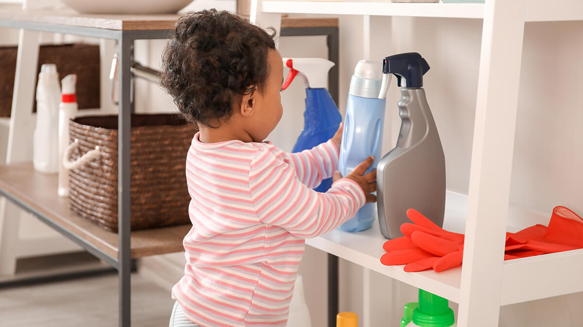A toddler among cleaning supply bottles