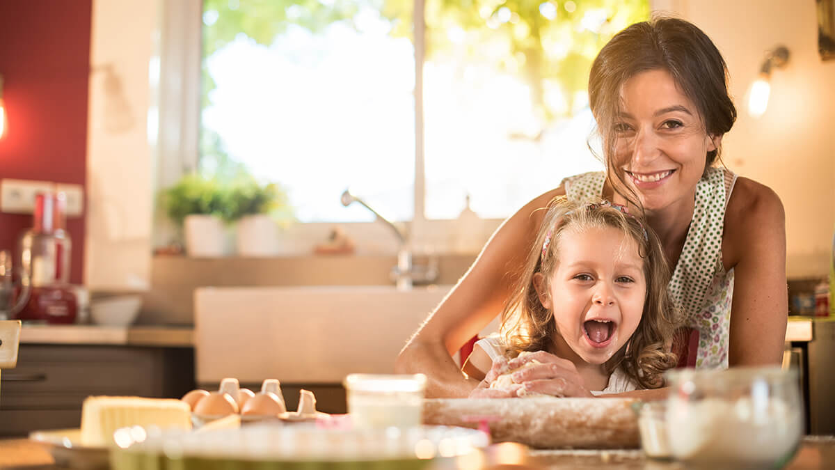 Young girl with Mom smiling with their hands full of flour from baking