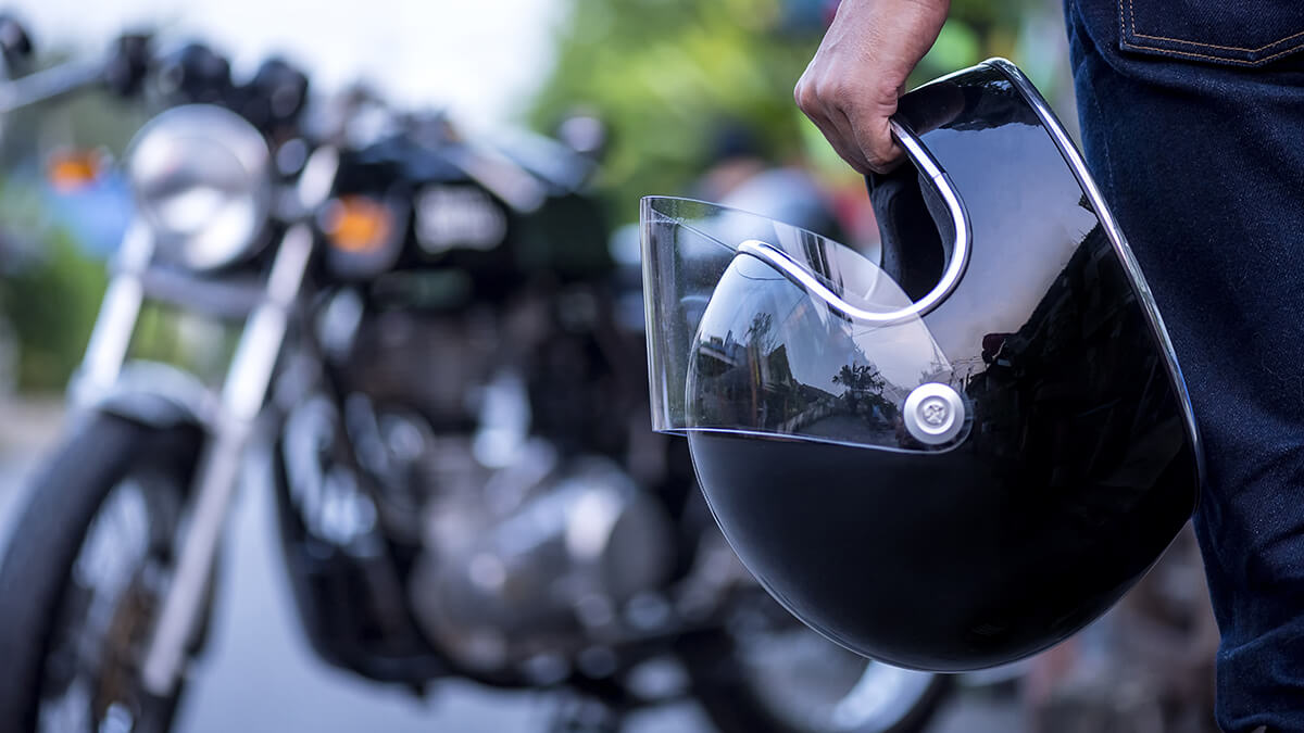 Close up of a motorcycle helmet with a motorcycle in the background