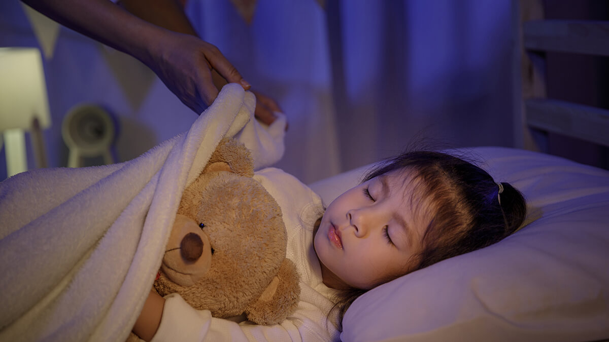 A child with her eyes closed holding a teddy bear