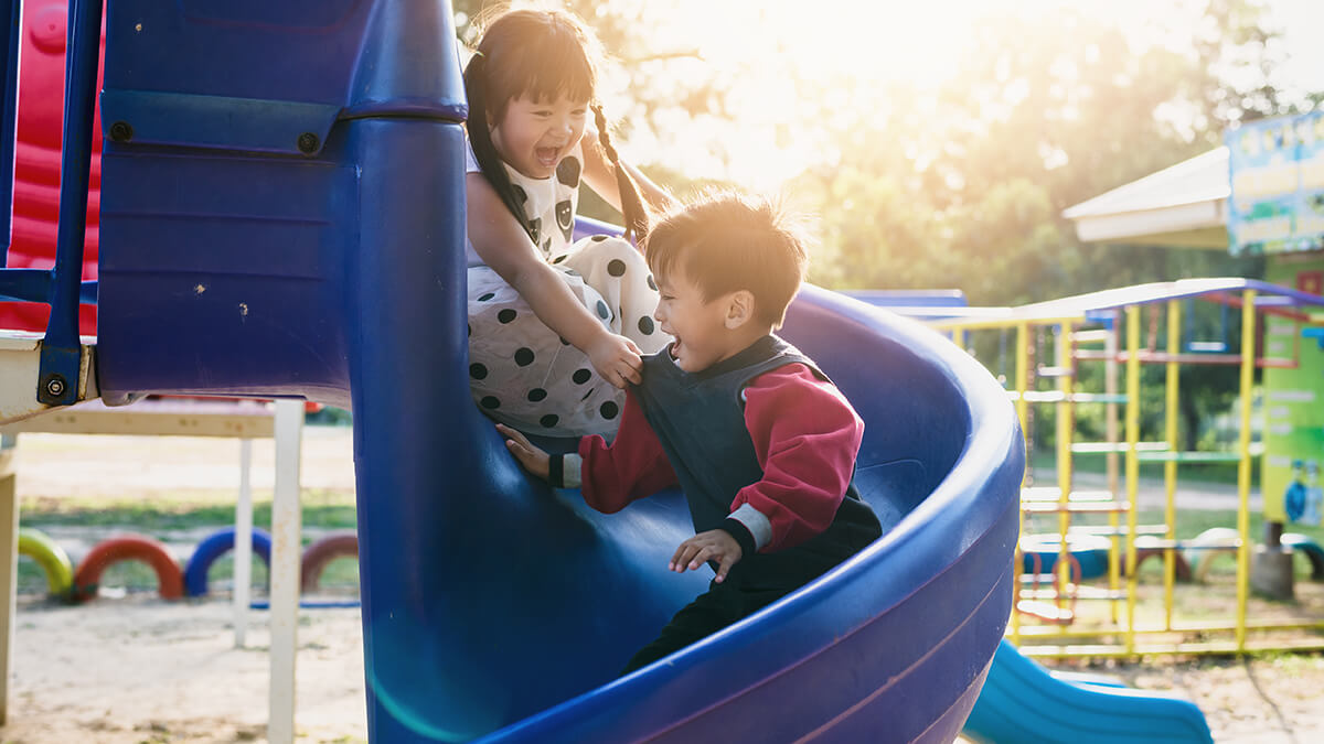 A girl and boy sliding down a twisting slide