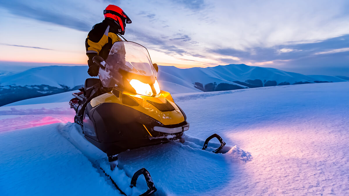 A snowmobiler in the moutains at dusk