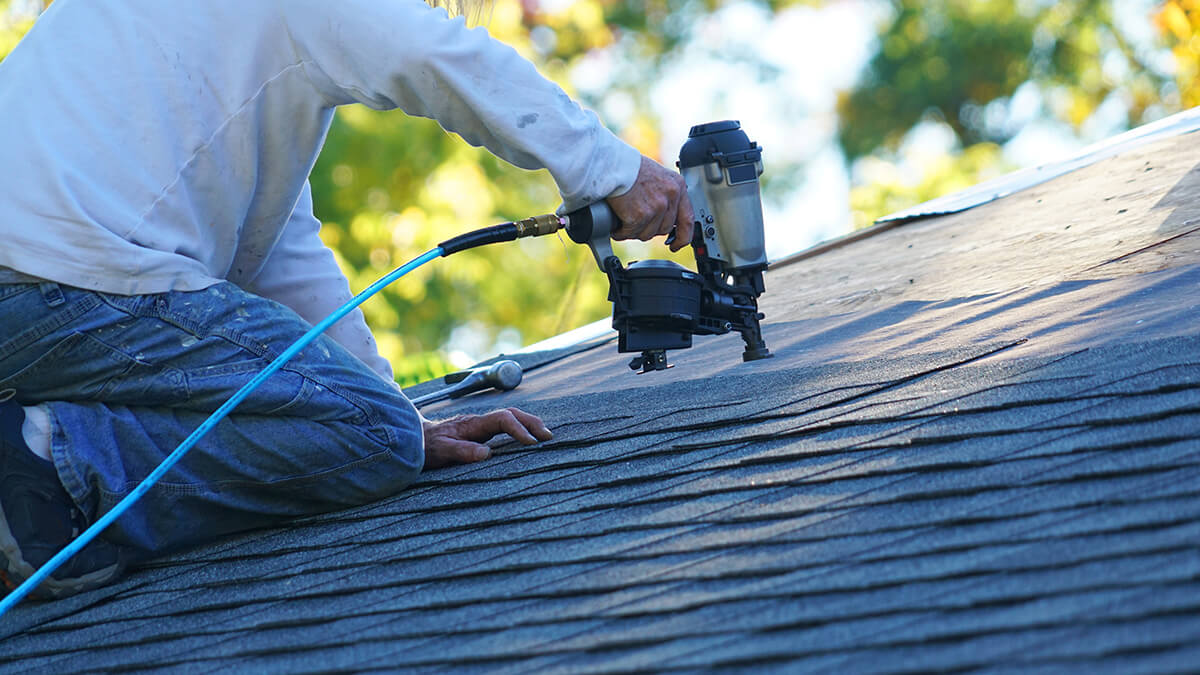 Man working on partially shingled roof