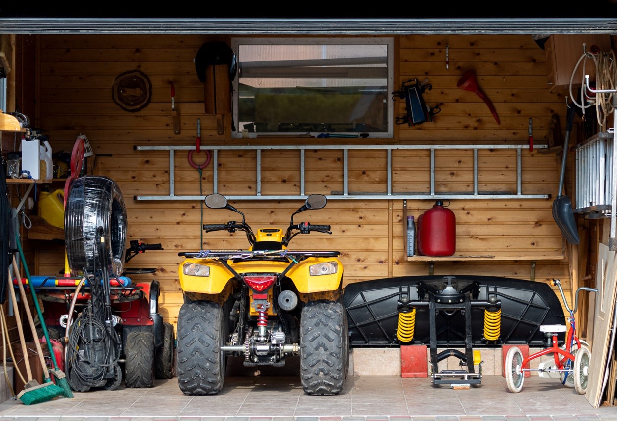 Two ATV's parked in a garage with tools and equipment
