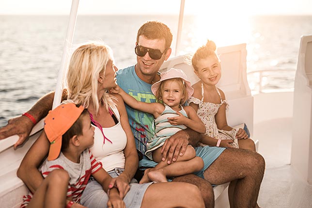 A family enjoying the open water on a boat as the sun shimmers onthe water