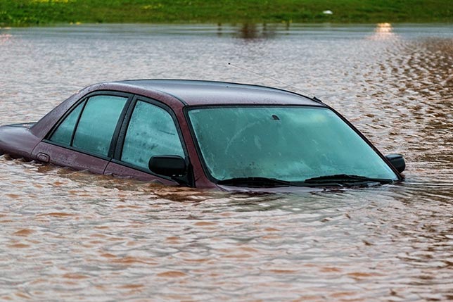 A car submerged in dark murky flood waters aimlessly yet dreadfully floating away