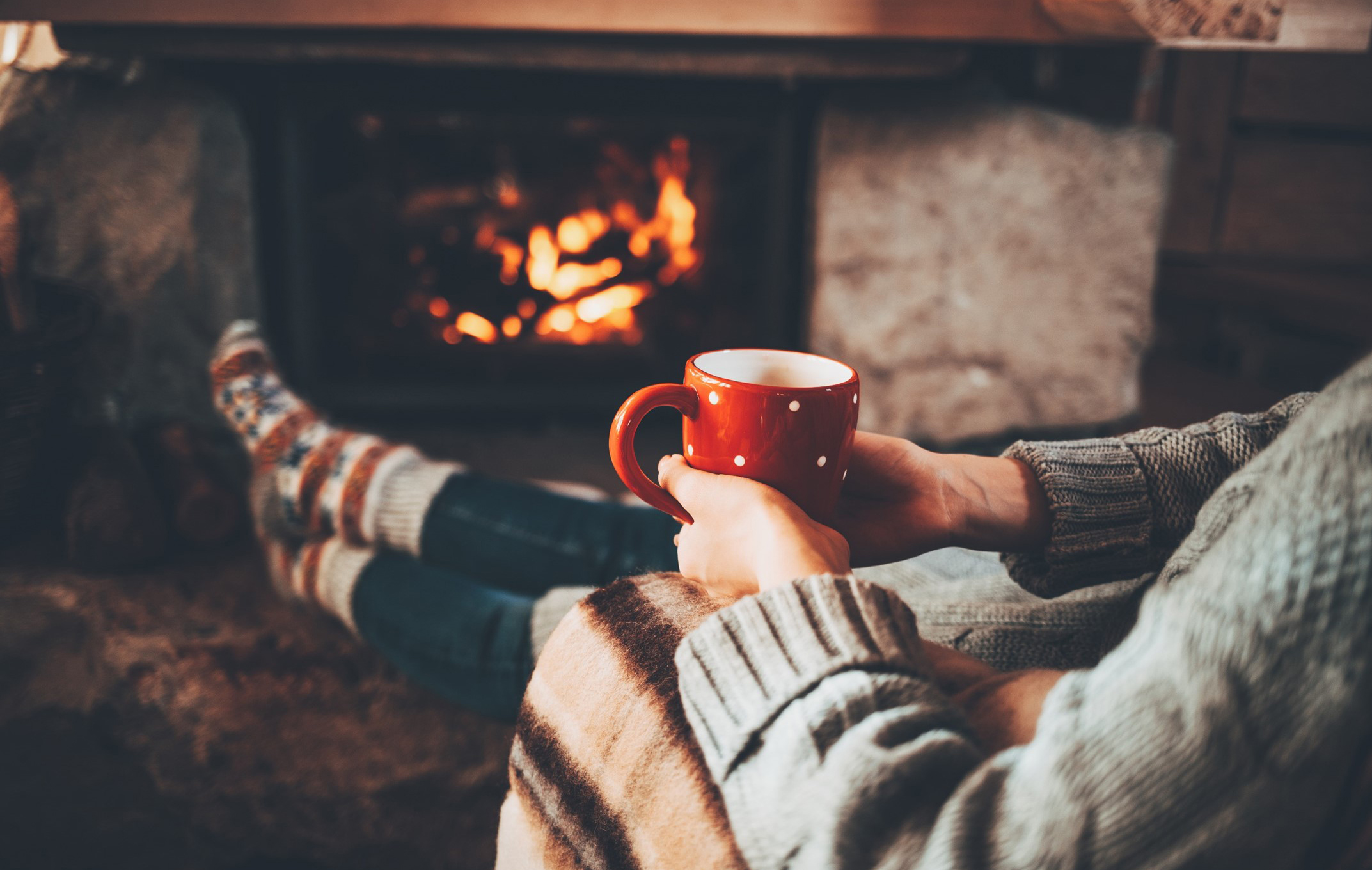 Woman enjoying a coffee in front of fire