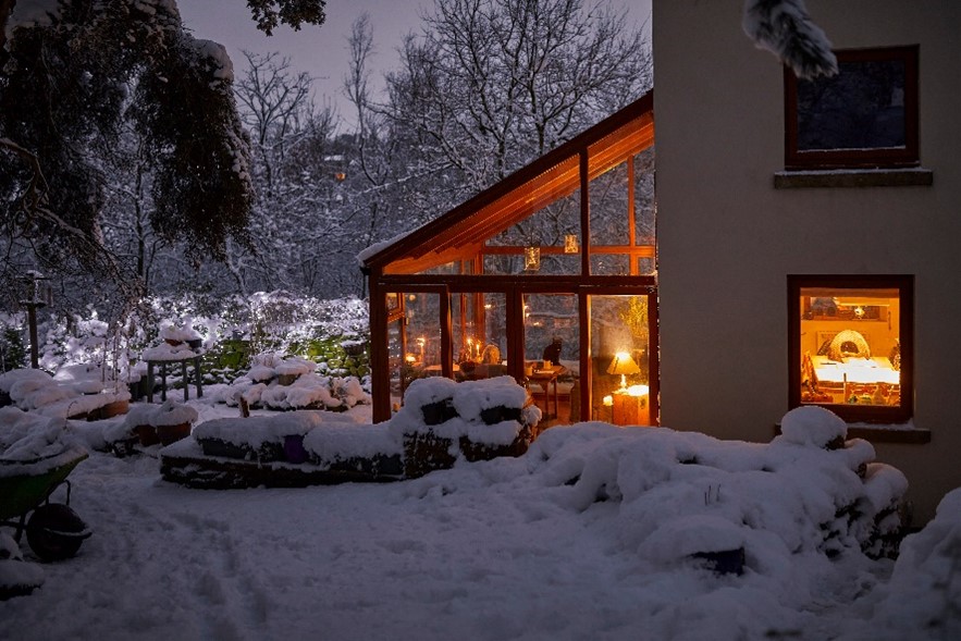 Beautifully lit glassed-in room surrounded by wintery snow-covered scene outside