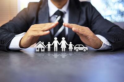 A business person uses his hands to cover a graphic of a home, family and car.