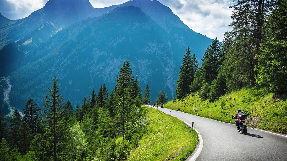 A motorcycle rider driving through a scenic moutain road