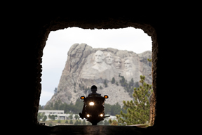 Motorcycle riding through tunnel with Mount Rushmore in the background