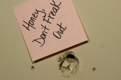 A hole in the drywall with a sorry note