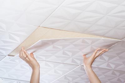 A close-up of hands installing a ceiling panel