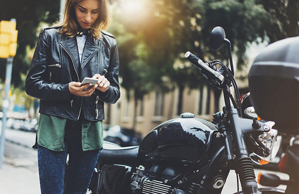 A parked motorcycle rider interacting with her phone