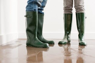Two people in rain boots standing on a wet floor