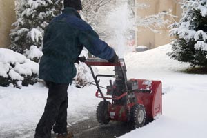 A homeowner snowblowing his sidewalk on a cold wintery day